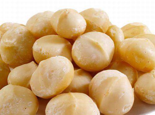 A pile of almonds on a white plate, macadamia nuts