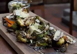 Chef Devon Junkin serves Brussels sprouts on a wooden tray with a jar at BO-beau kitchen + bar in Ocean Beach, CA.