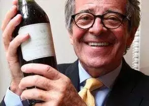 A man holding up a bottle of wine.