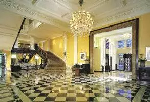 A large lobby with a checkered floor and a chandelier at Claridge's.