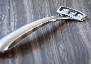 A stainless steel Zaffiro razor on a wooden surface.