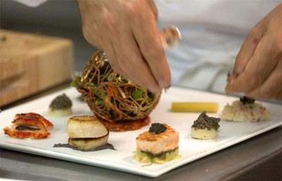 A chef is preparing a relish on a white plate.