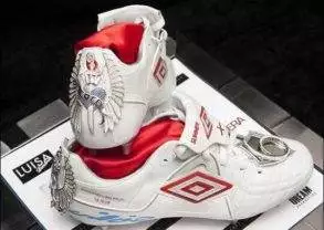 A pair of white soccer shoes with a red and white design priced at $128.
