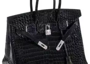 A black crocodile skin handbag with diamonds on a white background.