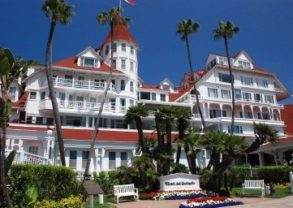 A large white building with palm trees in front of it, offering a truly memorable stay at the legendary Hotel del Coronado.
