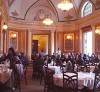 Elegant restaurant with round tables, chandeliers, arched windows, and people dining in a grand room, where the menu features Southern Comfort Food inspired by B. Smith’s celebrated culinary traditions.