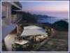 Outdoor restaurant patio with tables and umbrellas overlooking a rocky coastline at sunset, reminiscent of the stunning views found at Carmel’s Tickle Pink Inn, where rooms with a view enhance every dining experience.