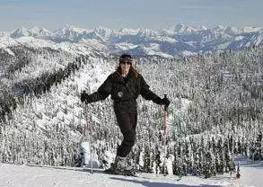 A woman on skis standing on a snow covered slope in Montana's Glacier Country.