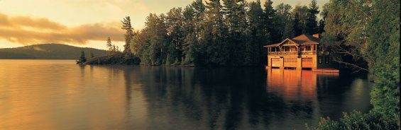 A luxurious house on the edge of a lake at sunset.