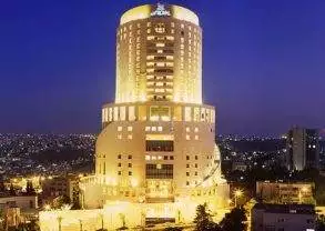 Le Royal Hotel, a large building lit up at night with a city in the background, embodies the heartbeat of Amman.