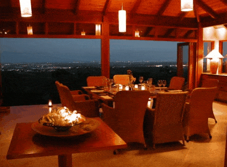 A dining room with a view of the city and mountains at night.