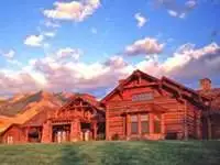 A large log home in the middle of a grassy field at Sun Ranch.