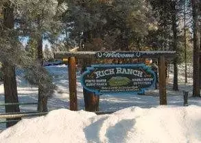 A sign with snow on it in front of a lodge in Montana's Hooked on Snowmobiling::Glacier Country.