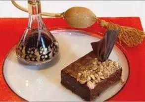 A dessert on a plate with a bottle of liqueur, showcasing the passion of chocolate brownie.