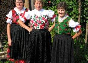 Three women in traditional Polish costumes posing for a photo.