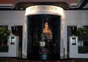 The entrance to a hotel with a sign that says Joel Robuchon At The Mansion.