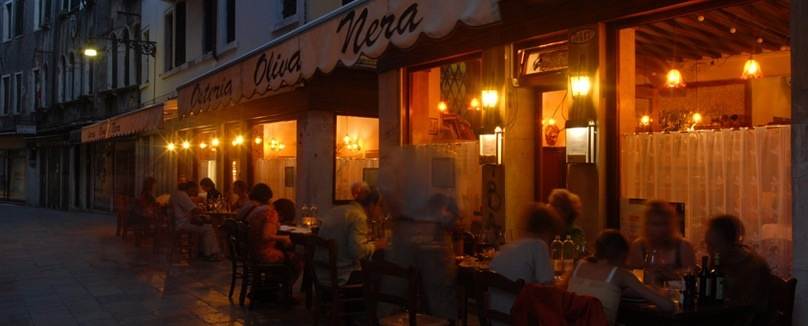 A group of people sitting at Olive Nera restaurant in Venice, Italy at night.