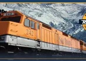 A train traveling through the mountains with mountains in the background.