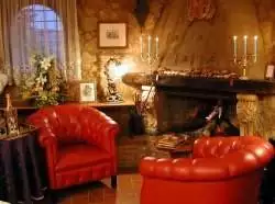 A living room with red chairs and a romantic fireplace, perfect for two to enjoy Italian preparations at Solo Per Du.