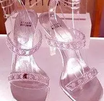 A pair of silver Cinderella slippers on display in a display case.