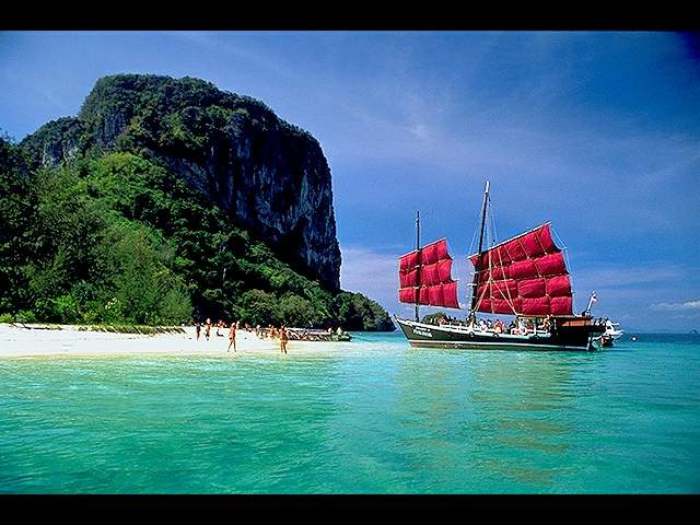 Savor A red Sailboat At Phuket Beach in Thailand.