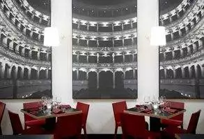 A restaurant with red chairs and a large painting on the wall where you can enjoy the show in the wine theatre.